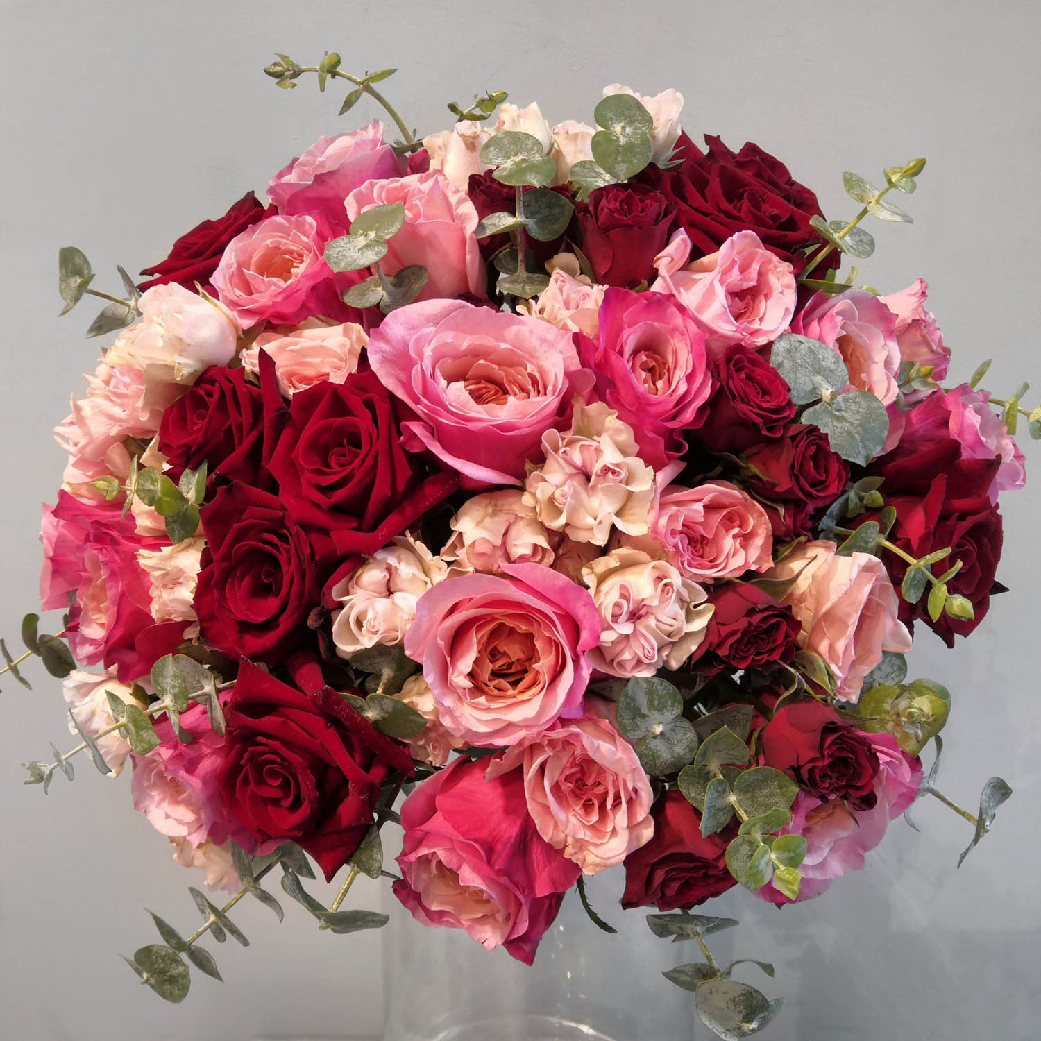 букет из классических роз с эвкалиптом, в розовых и красных оттенках