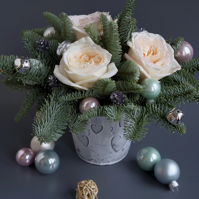 новогоднее украшение из еловых веток в горшочке с елочными игрушками и цветками бело-розовых роз